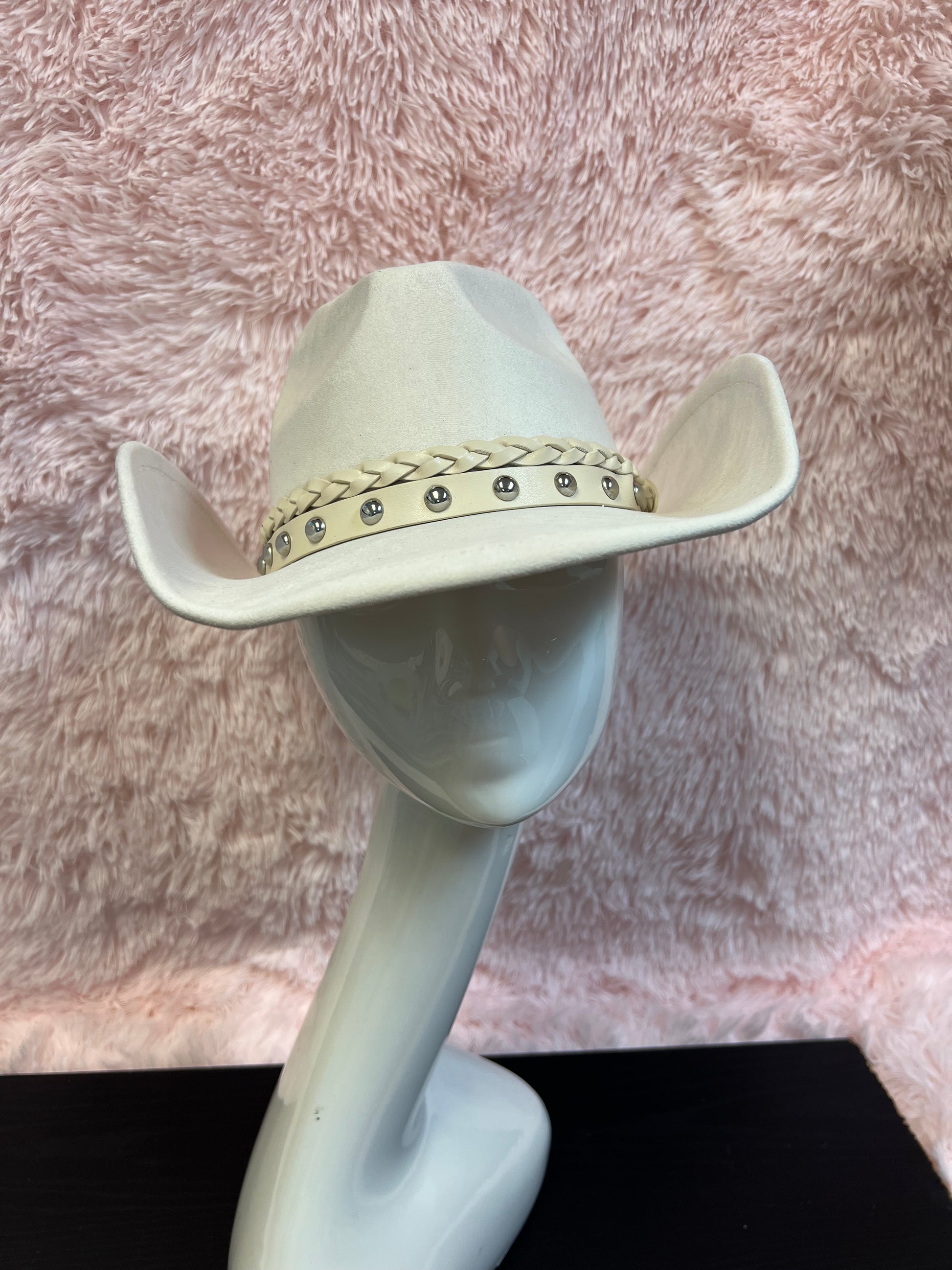 -faux suede cowboy hat in ivory

-all ivory faux leather band with braided and silver studded detail

-interior ribbon inside hat to customize size

-stiff, sturdy structure