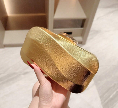 ORLA GOLD HARD CASE CLUTCH WITH SHINY METALLIC FABRIC OVER A MOULDED GEOMETRIC DESIGN