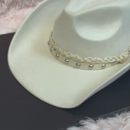 -faux suede cowboy hat in ivory

-all ivory faux leather band with braided and silver studded detail

-interior ribbon inside hat to customize size

-stiff, sturdy structure